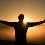 zac-durant-_6HzPU9Hyfg-unsplash man looking at a sunrise with open arms