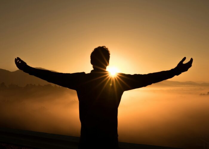 zac-durant-_6HzPU9Hyfg-unsplash man looking at a sunrise with open arms