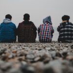 amir-hosseini-TvsKqeORBl4-unsplash Young men sitting on a beach