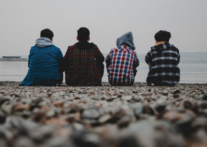amir-hosseini-TvsKqeORBl4-unsplash Young men sitting on a beach